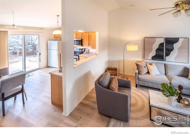 living room featuring ceiling fan, light hardwood / wood-style floors, and vaulted ceiling