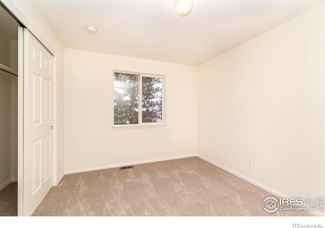 unfurnished bedroom with light colored carpet and a closet