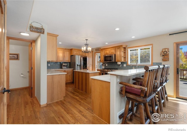 kitchen featuring appliances with stainless steel finishes, pendant lighting, tasteful backsplash, and a breakfast bar area