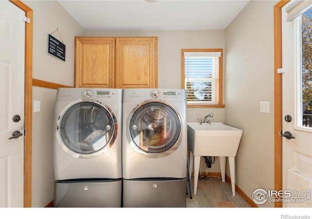 washroom featuring cabinets, washing machine and dryer, and light hardwood / wood-style floors