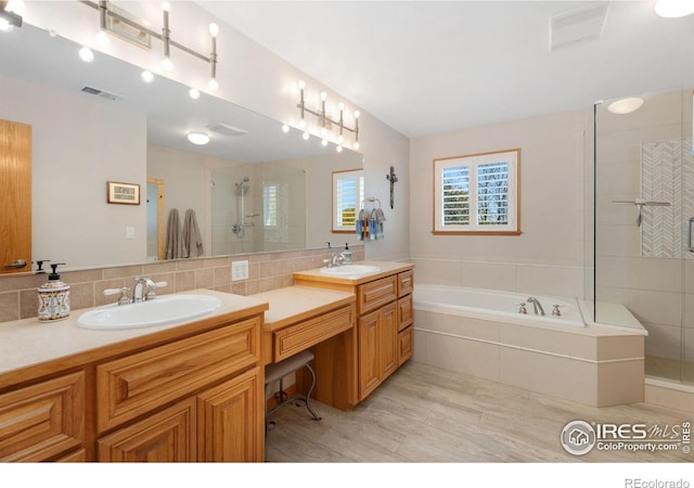 bathroom with backsplash, hardwood / wood-style floors, vanity, and independent shower and bath