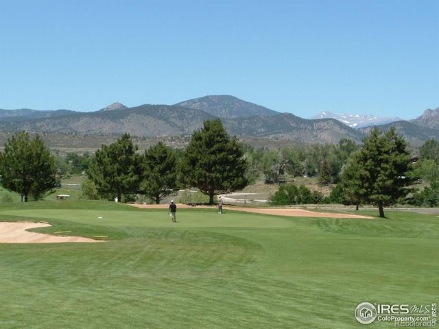 surrounding community with a mountain view and a yard