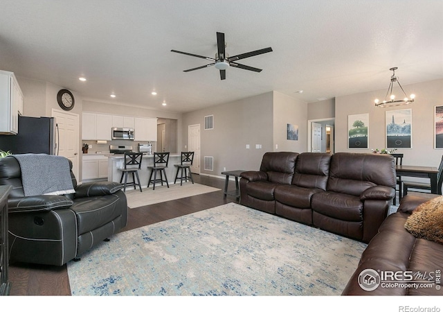 living room featuring ceiling fan with notable chandelier and wood-type flooring