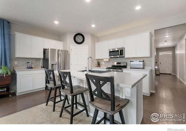 kitchen featuring appliances with stainless steel finishes, sink, white cabinets, a kitchen bar, and a kitchen island with sink