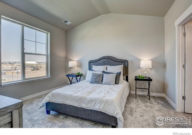 bedroom with vaulted ceiling and light colored carpet