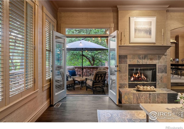 living room featuring a tile fireplace, dark hardwood / wood-style floors, and crown molding