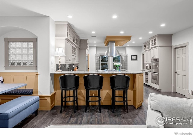 kitchen with kitchen peninsula, a breakfast bar, and dark wood-type flooring