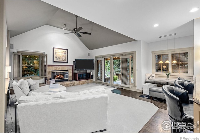 living room featuring hardwood / wood-style flooring, ceiling fan, high vaulted ceiling, and a tile fireplace