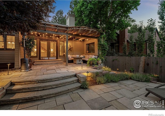 back house at dusk with an outdoor hangout area, a pergola, a patio, and french doors