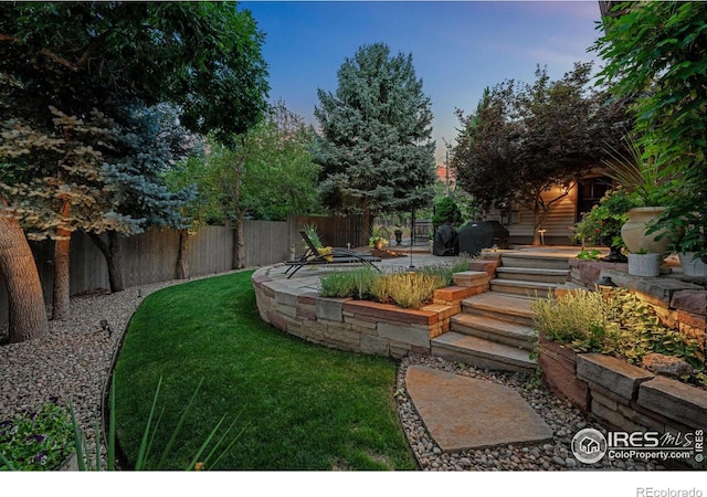 yard at dusk featuring a patio area