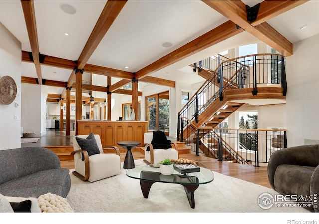 living room with a healthy amount of sunlight, beam ceiling, and light hardwood / wood-style floors