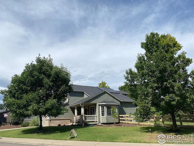 view of front of house with a front lawn, fence, and covered porch