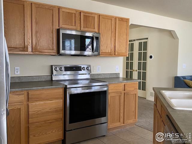 kitchen featuring light tile patterned floors, sink, appliances with stainless steel finishes, and french doors