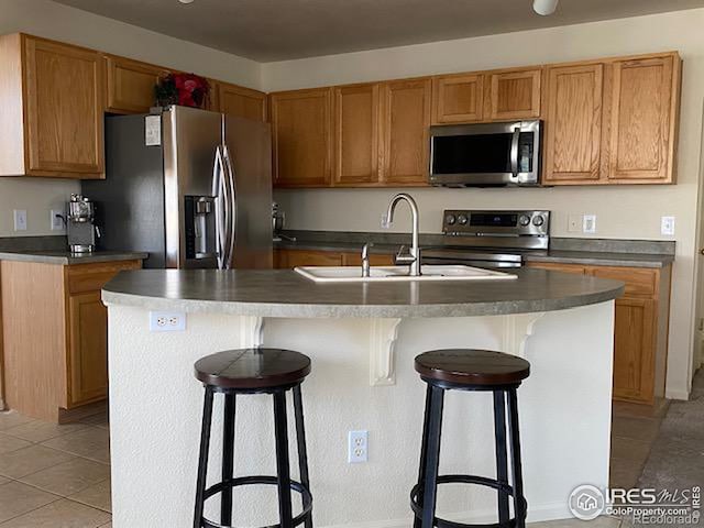 kitchen featuring a breakfast bar, sink, stainless steel appliances, and an island with sink