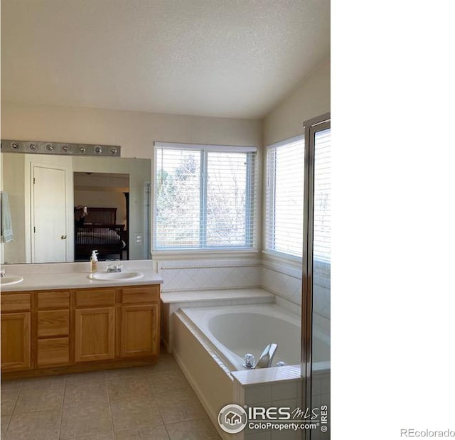 bathroom featuring a washtub, a healthy amount of sunlight, a textured ceiling, and tile patterned flooring