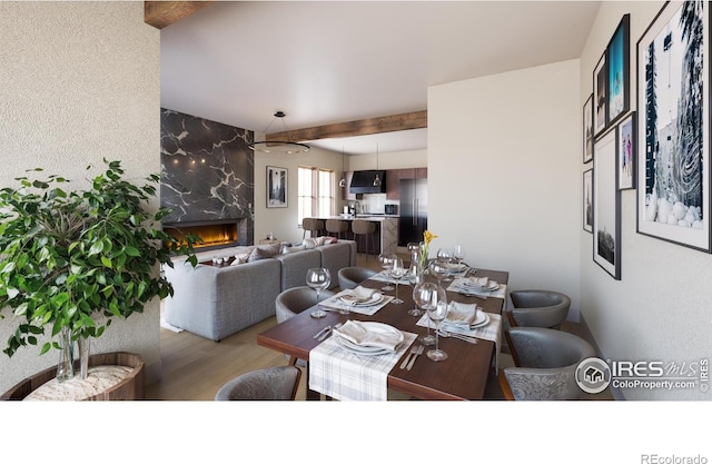 dining area featuring hardwood / wood-style floors, beam ceiling, and a premium fireplace