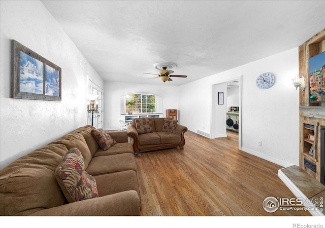 living room with hardwood / wood-style flooring, ceiling fan, and a textured ceiling