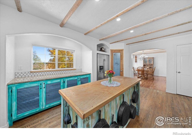 dining room featuring beamed ceiling, a chandelier, and dark hardwood / wood-style floors