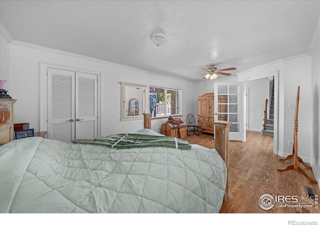 bedroom with hardwood / wood-style floors, french doors, crown molding, ceiling fan, and a closet