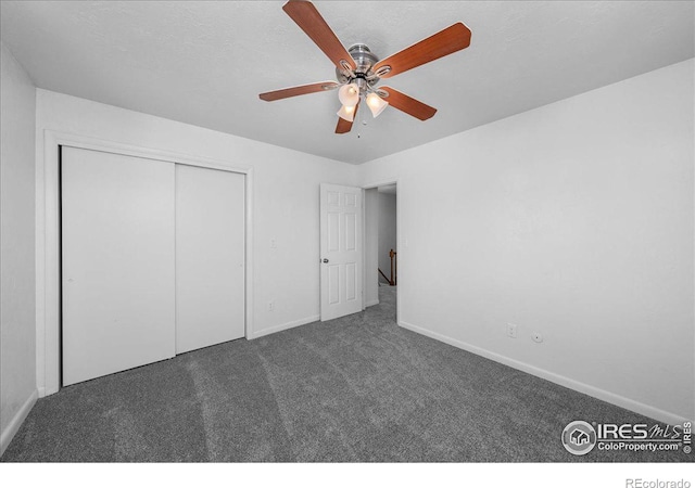 unfurnished bedroom with dark colored carpet, a closet, and ceiling fan