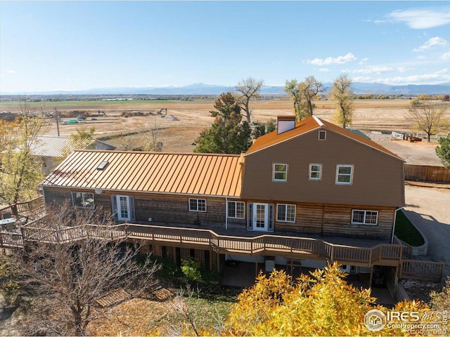 back of property featuring a rural view, a deck with mountain view, and french doors