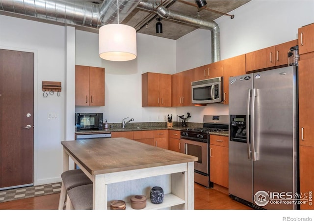 kitchen featuring sink, a towering ceiling, and appliances with stainless steel finishes