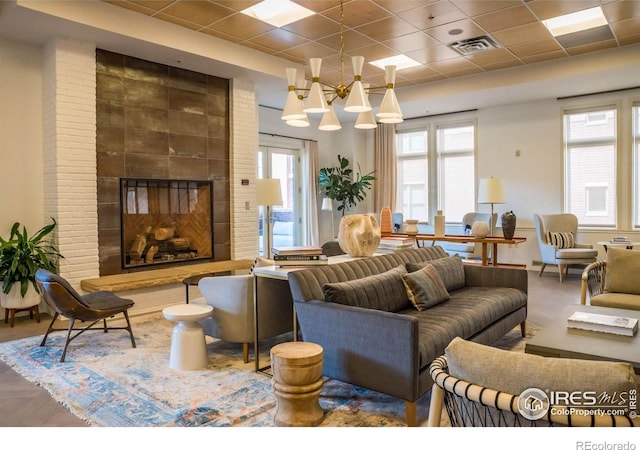 interior space featuring a large fireplace, plenty of natural light, a drop ceiling, and a notable chandelier