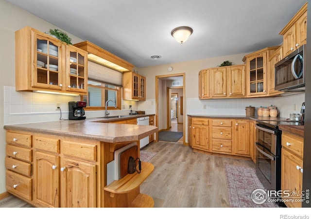 kitchen with sink, kitchen peninsula, stainless steel appliances, light hardwood / wood-style floors, and backsplash