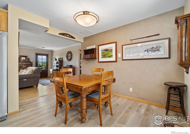 dining room with crown molding and light hardwood / wood-style flooring