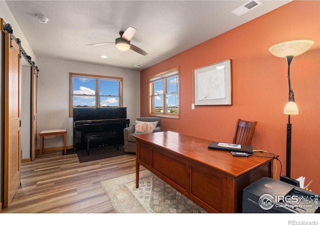 office area with ceiling fan, a barn door, and light hardwood / wood-style flooring