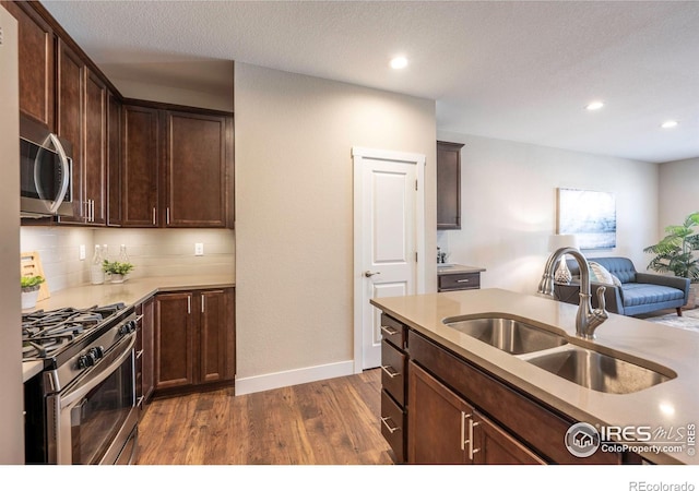 kitchen with dark wood-style floors, appliances with stainless steel finishes, light countertops, and a sink