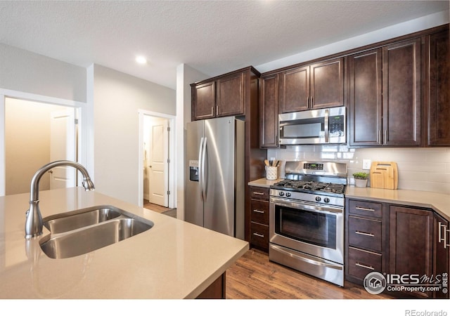 kitchen with stainless steel appliances, light countertops, a sink, and decorative backsplash