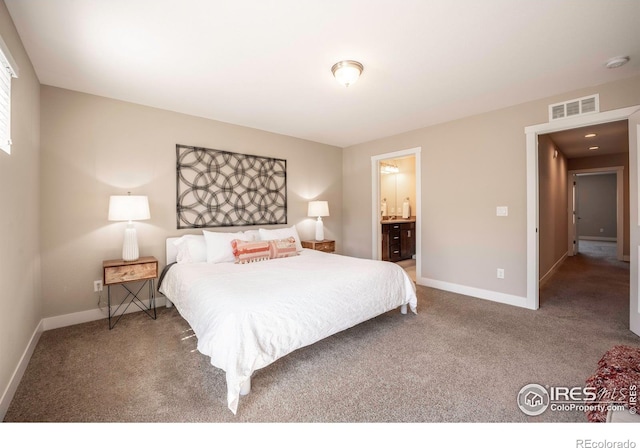 carpeted bedroom featuring ensuite bath, baseboards, and visible vents