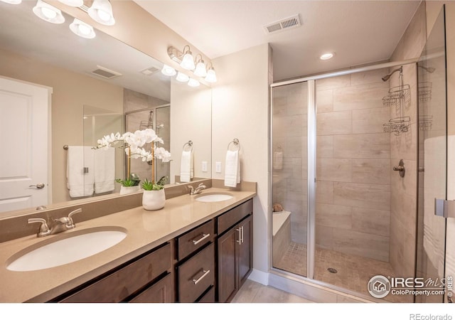 full bathroom with a stall shower, visible vents, and a sink