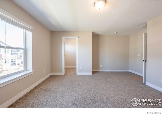 empty room featuring baseboards and light colored carpet