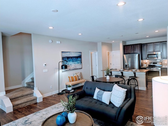 living room featuring baseboards, dark wood-type flooring, stairway, and recessed lighting