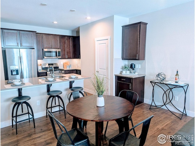 kitchen with appliances with stainless steel finishes, light countertops, dark brown cabinets, and wood finished floors