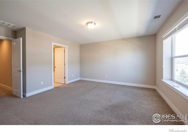 spare room with light colored carpet, visible vents, and baseboards