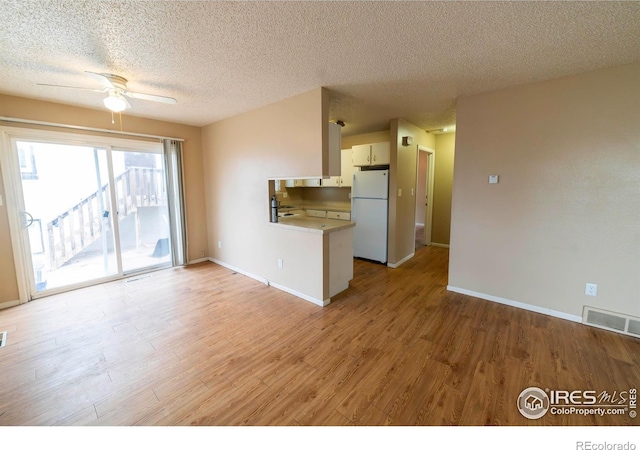 unfurnished living room featuring a textured ceiling, light hardwood / wood-style floors, and ceiling fan