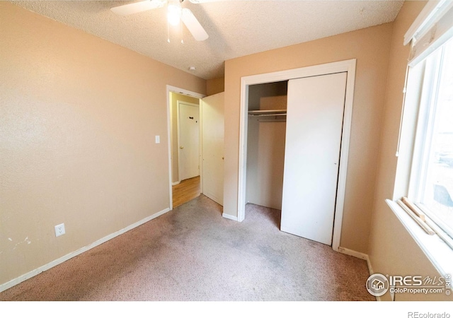 unfurnished bedroom featuring a textured ceiling, a closet, ceiling fan, and light colored carpet