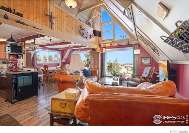 living room with wooden walls, high vaulted ceiling, a wealth of natural light, and dark wood-type flooring