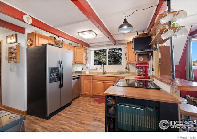 kitchen with beam ceiling, sink, stainless steel appliances, light brown cabinetry, and light wood-type flooring