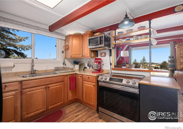 kitchen with beamed ceiling, sink, appliances with stainless steel finishes, and light hardwood / wood-style flooring