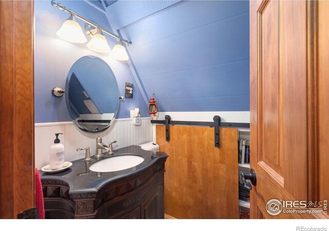 bathroom featuring wooden walls, vanity, and lofted ceiling