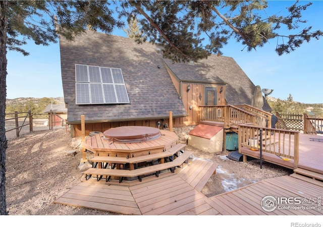 back of house with a deck with mountain view, a hot tub, and solar panels