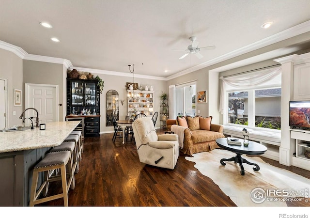 living room featuring dark hardwood / wood-style flooring, indoor wet bar, ceiling fan, and ornamental molding