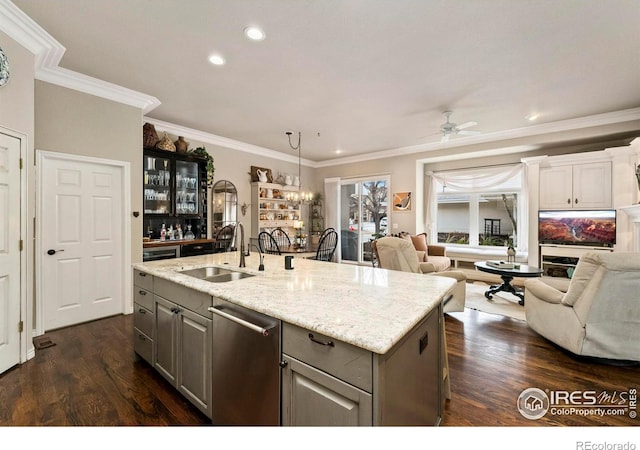 kitchen with stainless steel dishwasher, gray cabinetry, ceiling fan with notable chandelier, sink, and an island with sink