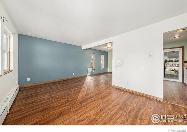 empty room with dark hardwood / wood-style floors and a baseboard heating unit