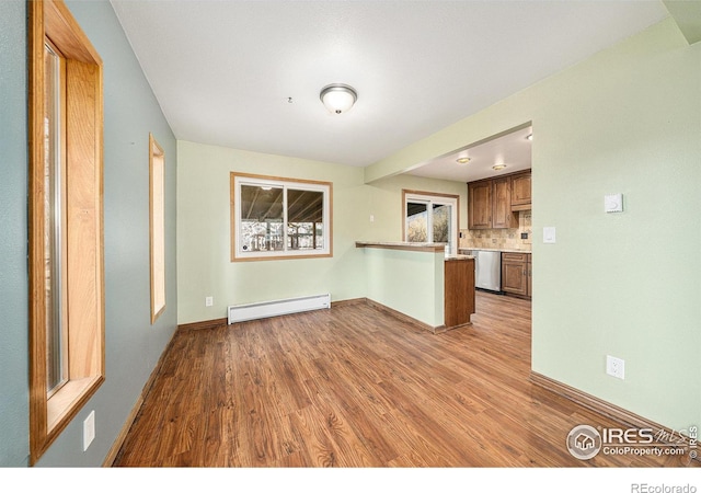 kitchen featuring baseboard heating, tasteful backsplash, stainless steel dishwasher, kitchen peninsula, and light hardwood / wood-style floors