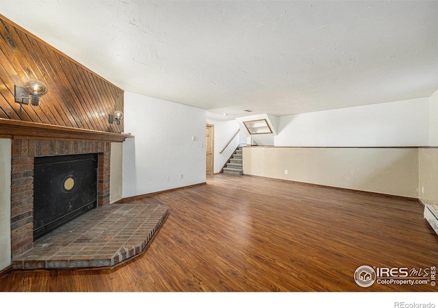 unfurnished living room with dark hardwood / wood-style floors and a brick fireplace